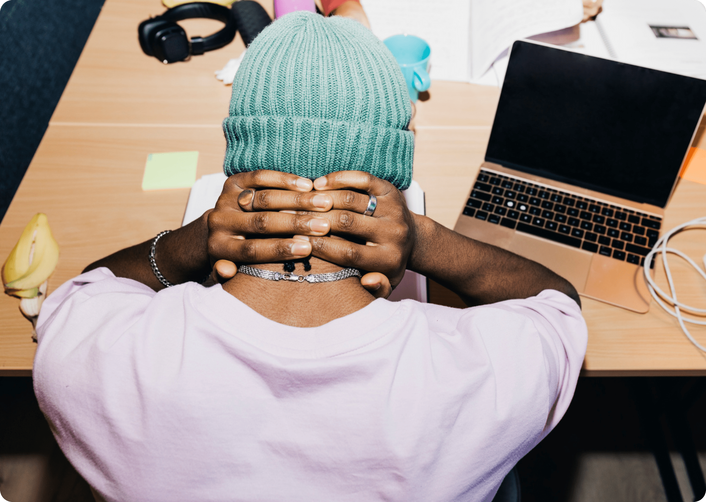 A renter sits at a desk with their hands behind their head, looking stressed at a laptop and bills, illustrating the strain of rent being due before payday.